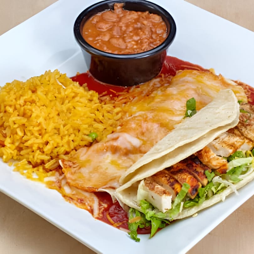 Mexican combo plate with yellow rice, refried beans, a cheesy enchilada, and a chicken taco.