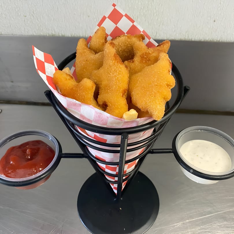 Dinosaur-shaped chicken nuggets and fries in a cone, with ketchup and ranch dipping sauces.